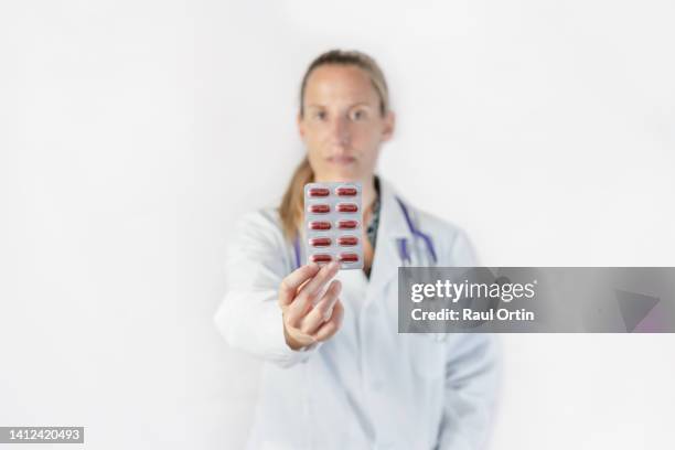 portrait of female doctor holding and showing at the camera blister pack of medication pills - blister pack stock-fotos und bilder