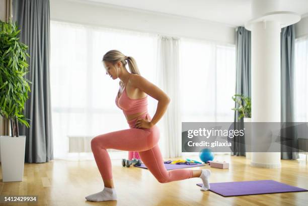 jovem mulher se exercitando em casa. - muscular contraction - fotografias e filmes do acervo