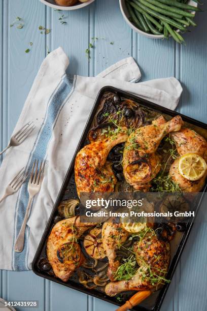 chicken legs baked with onions, lemon, olives, garlic and thyme - thigh stock photos et images de collection