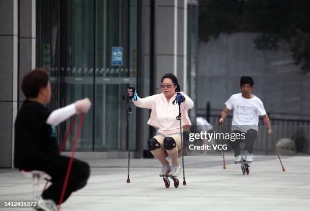 Retired elderly people crouch to keep balance on specially-made roller skaters on August 2, 2022 in Shenyang, Liaoning Province of China.