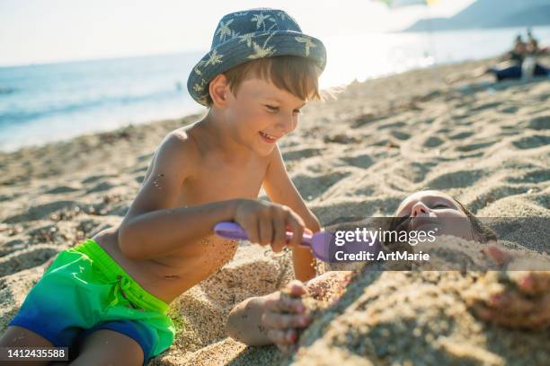 enfants jouant avec le sable sur la plage - digging beach photos et images de collection