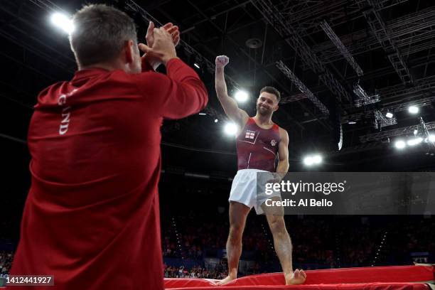 Giarnni Regini-Moran of Team England celebrates with a member of the coaching staff following their routine during Men's Vault Final on day five of...