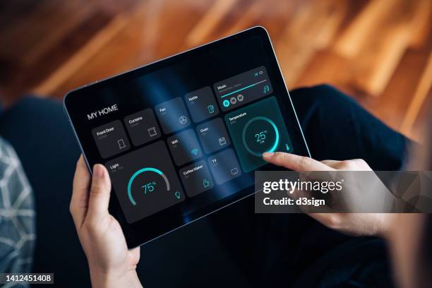 cropped shot of young woman setting up intelligent home system, controlling smart home appliances with control panel of a smart home. home automated system controlled from a dashboard. smart living. lifestyle and technology. smart home technology concept - ipad ストックフォトと画像