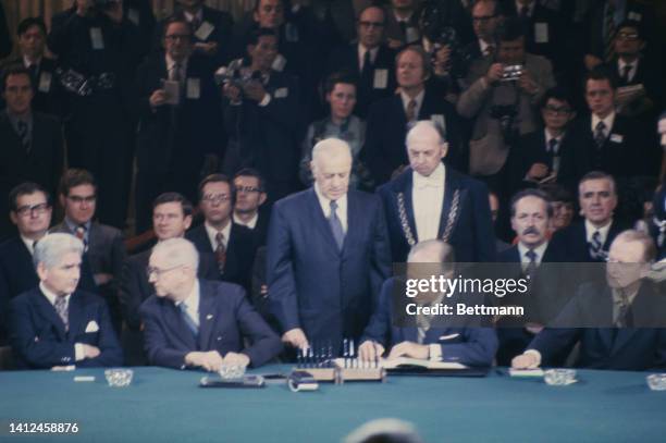 Secretary of State William Rogers signs the Vietnam cease-fire agreement. Stern-faced usher Leon Zinzius in background; U.S. Chief negotiator William...