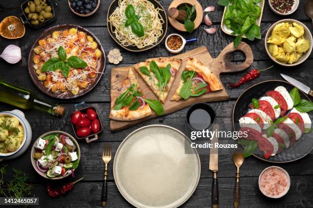 big dinner table with italian food, pizzas and pastas - spoil system stock pictures, royalty-free photos & images