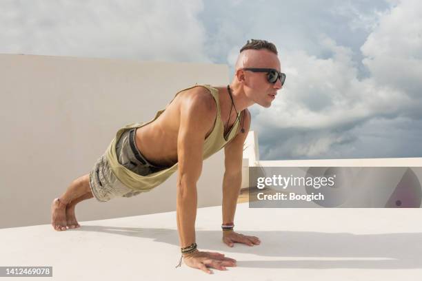 fit man in 40s exericising on rooftop holding plank position - short shorts stock pictures, royalty-free photos & images