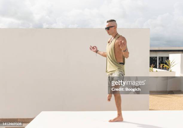 man standing in tree pose in meditation on a rooftop in summer - bare feet male tree stock pictures, royalty-free photos & images