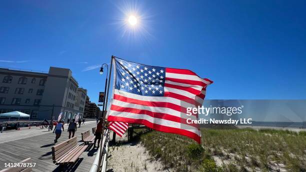 Gorgeous blue sky is overhead as the American flag billows in a light breeze along the boardwalk in Long Beach, New York, on July 4, 2022.