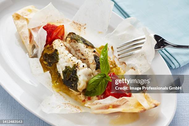 cod cooked in parchment paper with tomatoes and herbs - codfish imagens e fotografias de stock