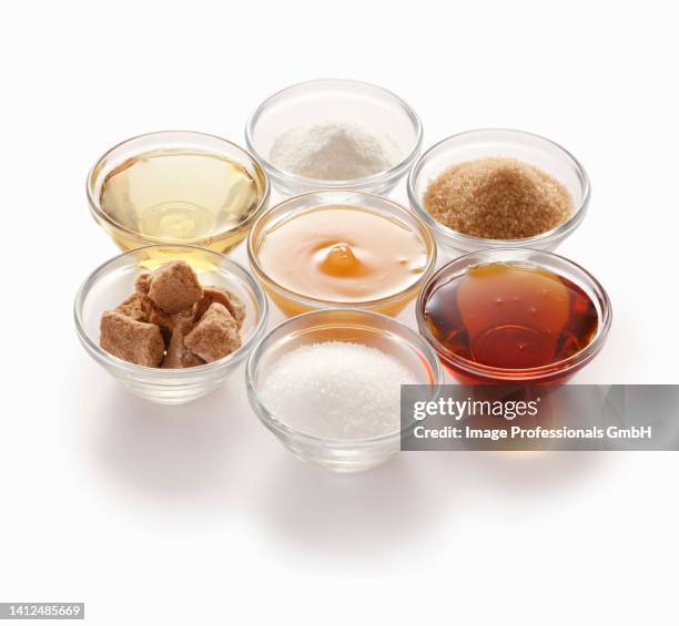 natural sweeteners – clockwise from top: stevia, cane sugar, maple syrup, beet sugar, coconut flower sugar, agave syrup and honey - honey stevia stock pictures, royalty-free photos & images