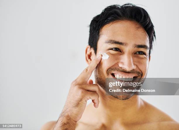 skincare, healthy skin and selfcare routine using moisturizer to achieve a clean and flawless complexion. handsome and happy male using cream to hydrate and protect while practicing good hygiene - skin care stock pictures, royalty-free photos & images