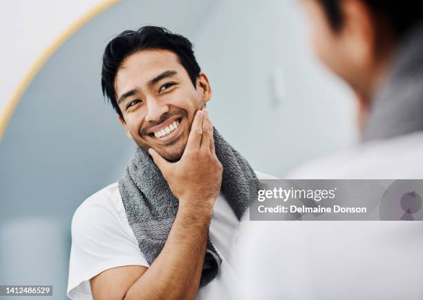 toelettatura, igiene e sana routine di cura della pelle del viso per una pelle maschile liscia e morbida. bel giovane che si guarda allo specchio toccandosi la barba felice del suo prodotto per la rasatura facciale - guy stubble foto e immagini stock