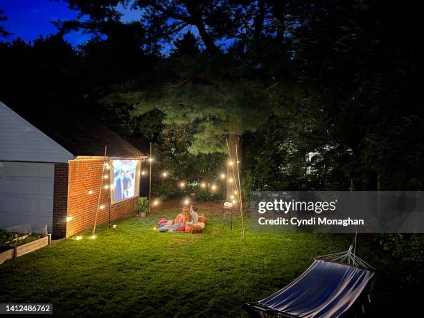 friends snuggled on a blanket for outdoor movie night - tuinscherm stockfoto's en -beelden