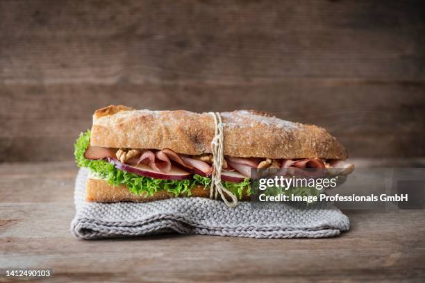 a baguette with serrano ham, walnut, apple and frisee lettuce - krulandijvie stockfoto's en -beelden