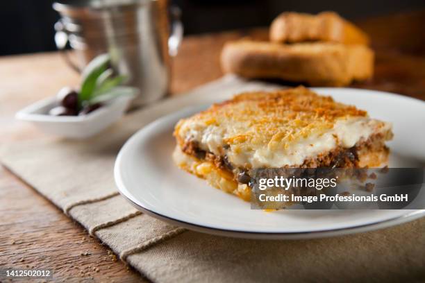 piece of greek mousaka served on a plate and bread on the background - moussaka stock-fotos und bilder