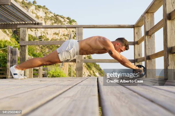 man exercising outdoors with an abdominal roller. outdoor sport concept - male stomach stock pictures, royalty-free photos & images
