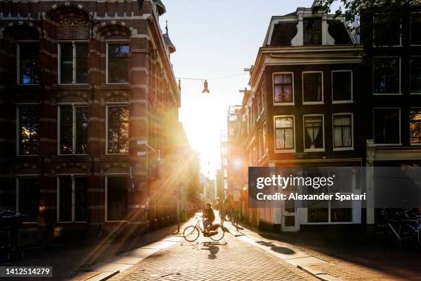 sun shining through the streets in amsterdam at sunset, netherlands - amsterdam bike stockfoto's en -beelden