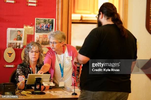 Poll workers help a voter with their ballot in the Kansas Primary Election at Merriam Christian Church on August 02, 2022 in Merriam, Kansas. Voters...