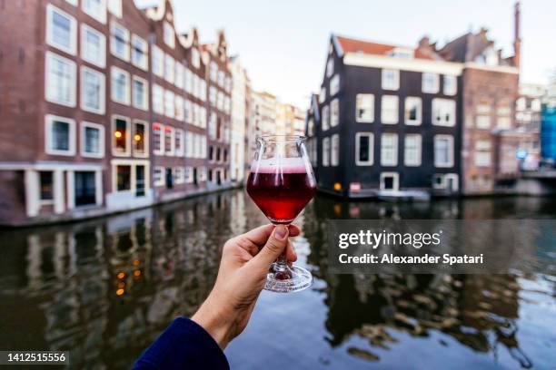 man drinking kriek beer (cherry beer) near canal in amsterdam, netherlands - sour cherry stock pictures, royalty-free photos & images