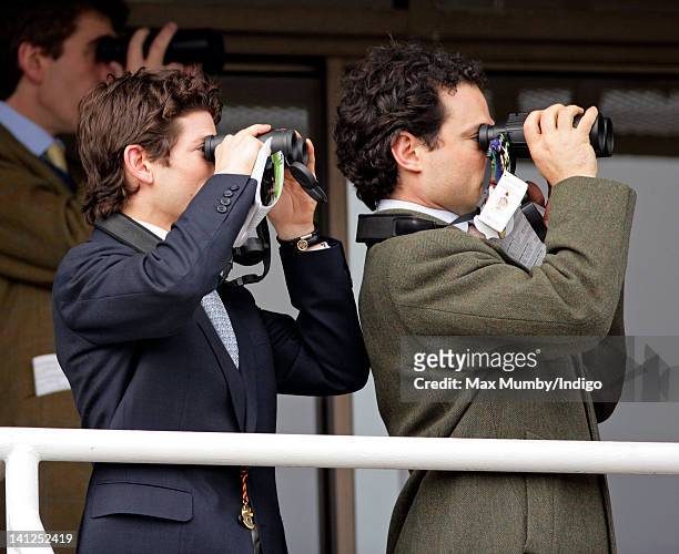 Sam Waley-Cohen and Marcus Waley-Cohen use binoculars to watch the racing as they attend day one of the Cheltenham Horse Racing Festival on March 13,...