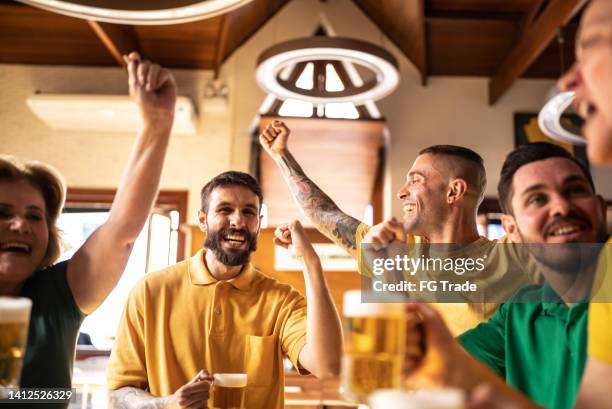 tifoso sportivo giallo e verde che festeggia e beve birra al bar - afl woman foto e immagini stock