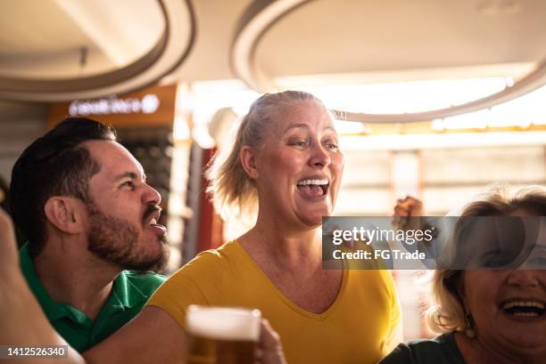 sports fan celebrating and drinking beer in a bar - saturday footy stock pictures, royalty-free photos & images