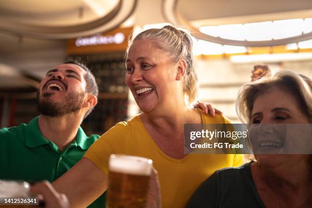sports fan celebrating and drinking beer in a bar - saturday footy stock pictures, royalty-free photos & images
