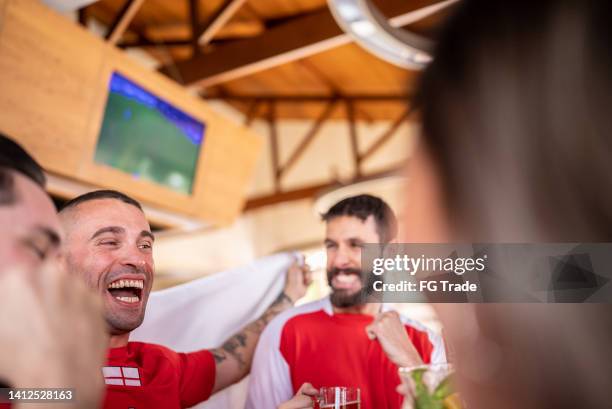 mid adult men celebrating english team winning in a bar - england fans stock pictures, royalty-free photos & images