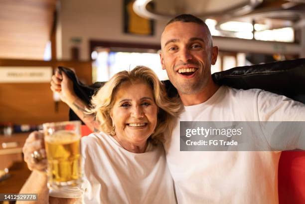 porträt von deutschen mutter-sohn-fans, die sportspiele beobachten und in einer bar feiern - fußball fan oma stock-fotos und bilder