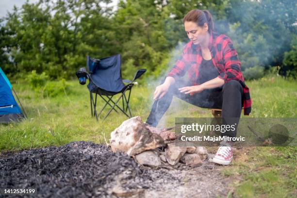 a woman camp fire cooking in the wilderness - woodland cafe stock pictures, royalty-free photos & images