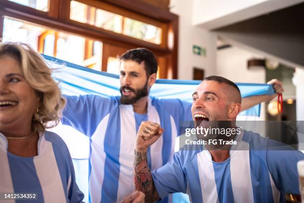 amigos celebrando la victoria del equipo argentino en un bar - futbol argentino fotografías e imágenes de stock
