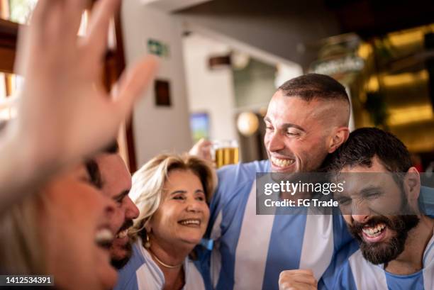 sports fan friends celebrating game winning in a bar - football argentine stock pictures, royalty-free photos & images