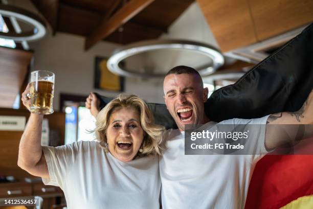 porträt von deutschen mutter-sohn-fans, die sportspiele beobachten und in einer bar feiern - fußball fan oma stock-fotos und bilder