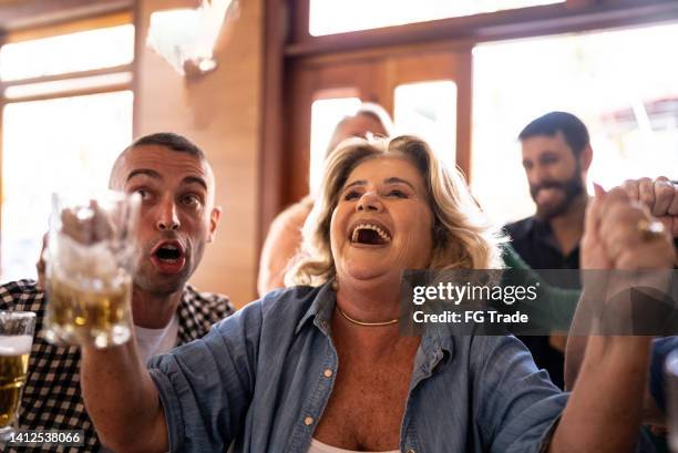 freunde, die feiern, während sie ein spiel in einer bar sehen - fußball fan oma stock-fotos und bilder