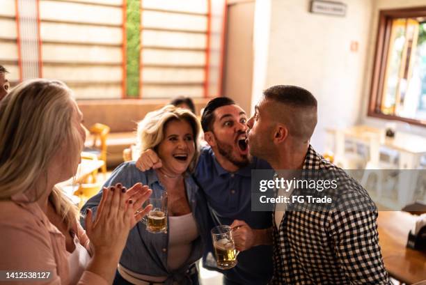 happy friends watching a match and celebrating in a bar - social tv awards stockfoto's en -beelden