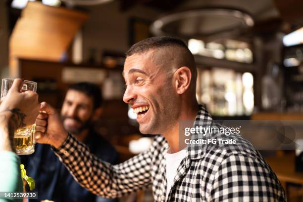 mid adult man talking and drinking a beer at a bar - friday stock pictures, royalty-free photos & images