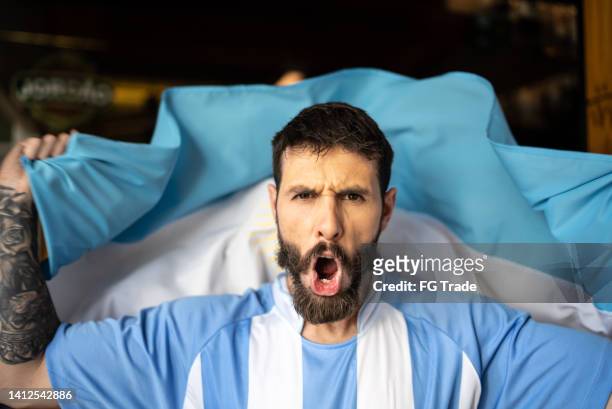 portrait of an argentinian team fan celebrating with argentinian flag - football argentine stock pictures, royalty-free photos & images