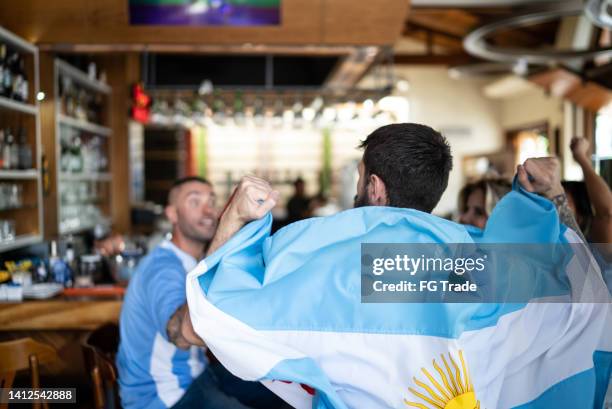 rear view of argentinian team fan with an argentinian flag in a bar - social tv awards stockfoto's en -beelden