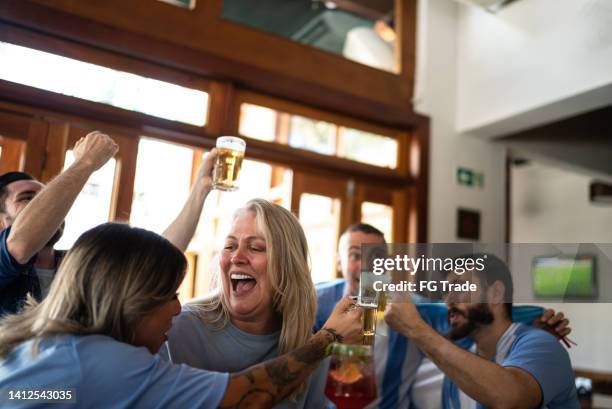 sport team fans celebrating while watching a match in a bar - latino media awards stock pictures, royalty-free photos & images