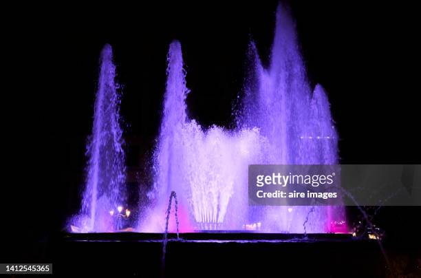 fountain with water jets illuminated by colored lights that can be seen in the darkness of the night. - fashion show stock pictures, royalty-free photos & images