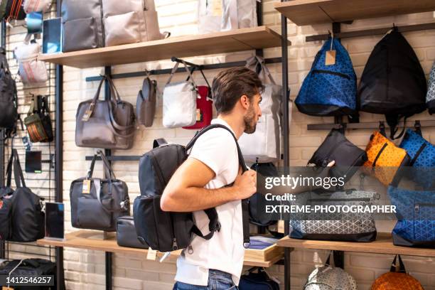young man with a backpack seen choosing the right accessory in a travel bags store - accessory stockfoto's en -beelden
