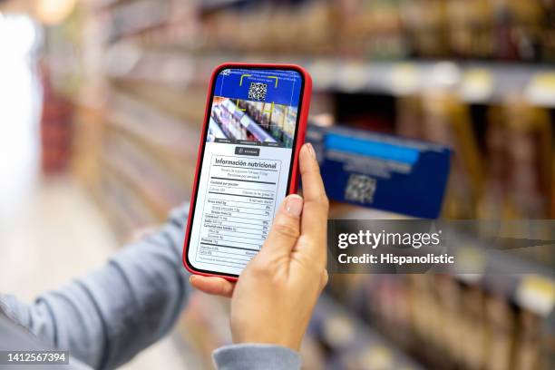 donna che fa la spesa al supermercato e scansiona un'etichetta con il suo cellulare - lettore di codice a barre foto e immagini stock