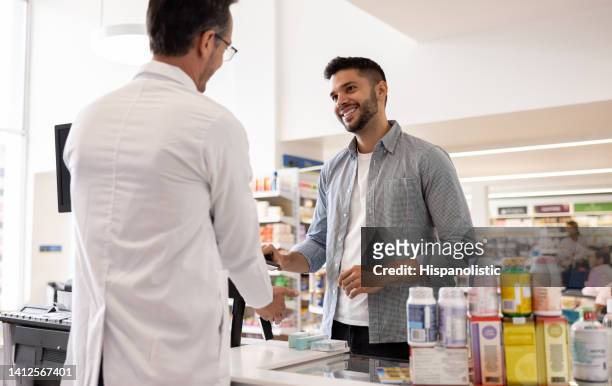 hombre comprando medicamentos en la farmacia - farmacia fotografías e imágenes de stock