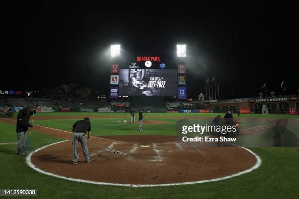 The San Francisco Giants grounds crew works on the field after their game against the Los Angeles Dodgers as a tribute to Vin Scully is shown on the...