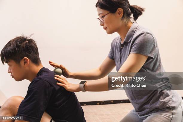 asian man being treated by a physical therapist - massagebal stockfoto's en -beelden