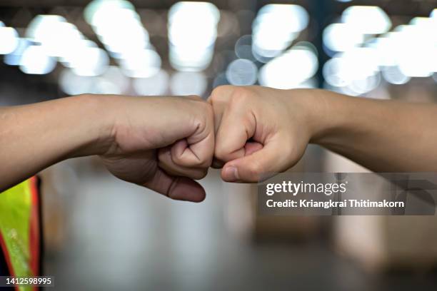 two male workers are giving fist bumps. - fist bump fotografías e imágenes de stock