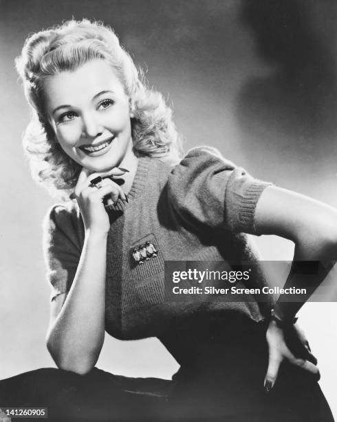 Ginger Rogers , US actress and dancer, wearing a short-sleeve knitted top, posing with her chin resting on her right hand in a studio portrait, circa...