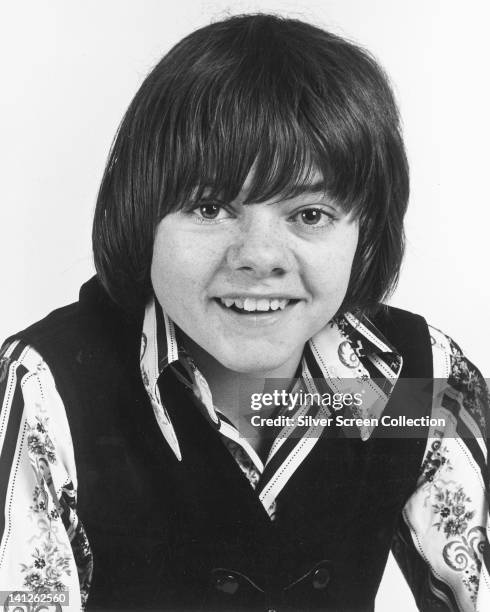 Jack Wild , British actor, wearing a black tank top over a print pattern shirt in a studio portrait, against a white background, circa 1965.