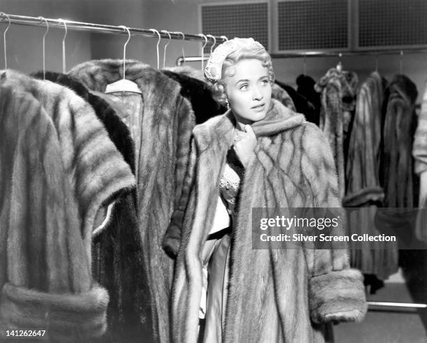 Jane Powell, US actress and singer, wearing a fur coat, surrounded by rails of fur coats, in a publicity still issued for the film, 'Small Town...