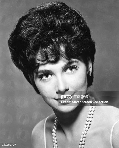 Headshot of Suzanne Pleshette , US actress, wearing a pearl necklace in a studio portrait, against a dark background, circa 1965.